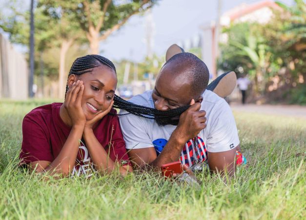 Man and woman lying on green grass having a romantic moment