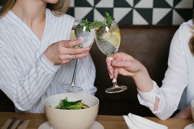 Anonymous friends clinking glasses in cafe