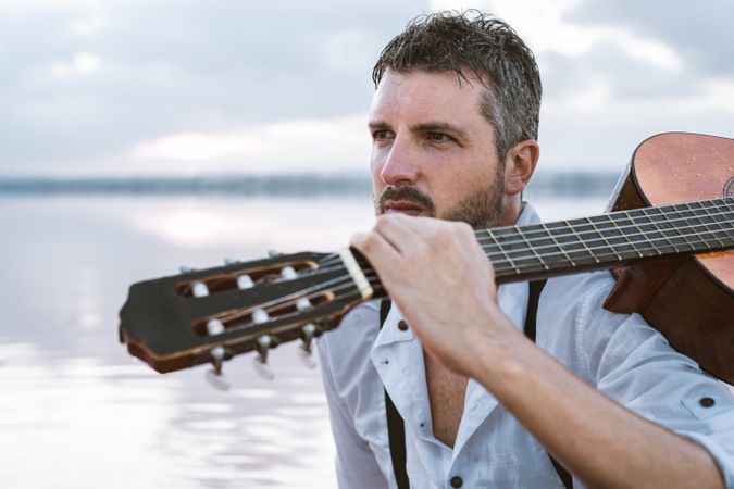 Musician with guitar on pink sandy water