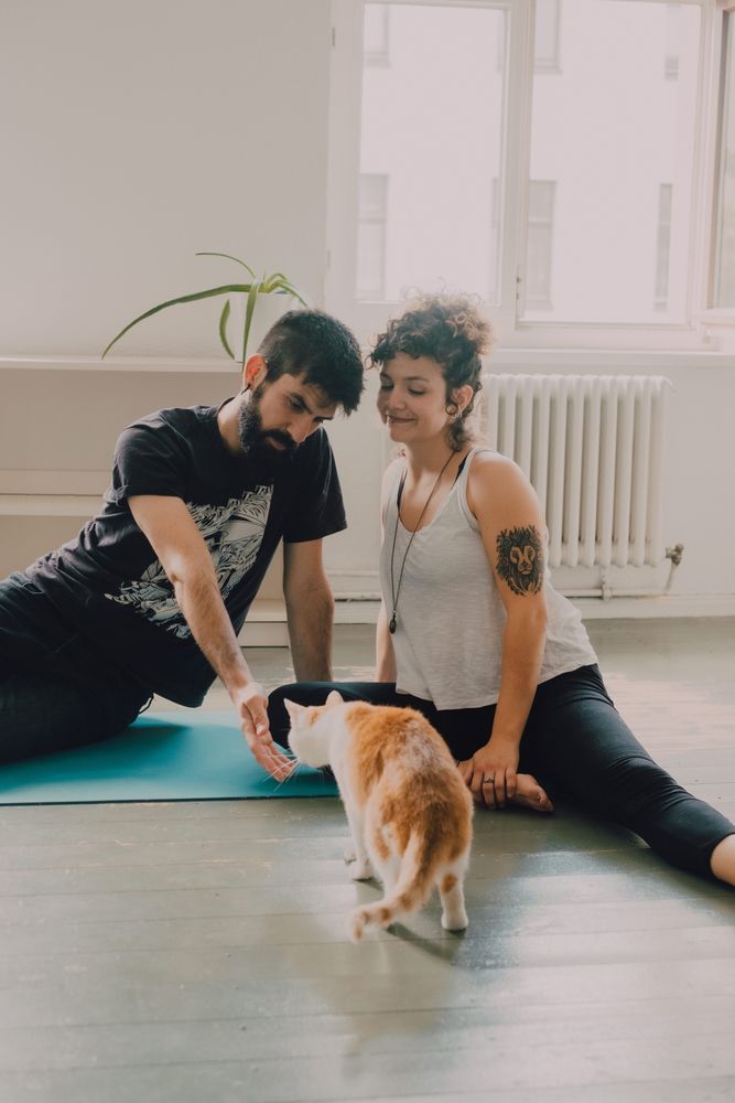 Loving couple cuddling on floor while cat walking around