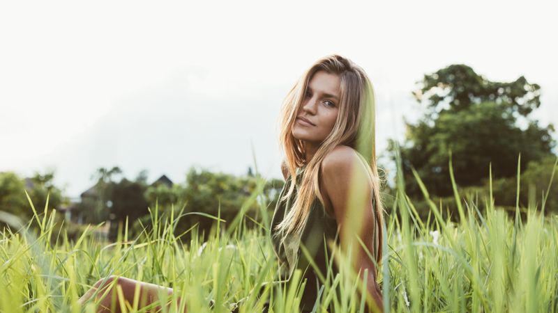 Portrait of cute young female model sitting in the meadow