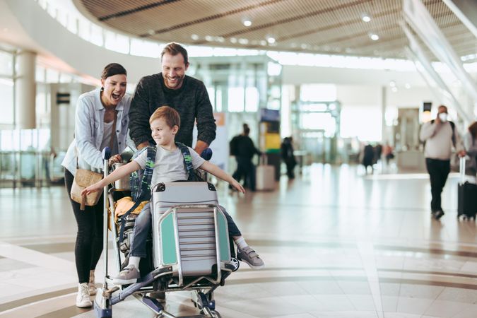 Couple happily pushing the trolley with their son at airport