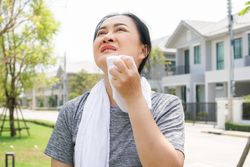 Woman using towel to wipe face after workout