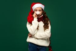 Girl in Santa hat holding pompom to nose