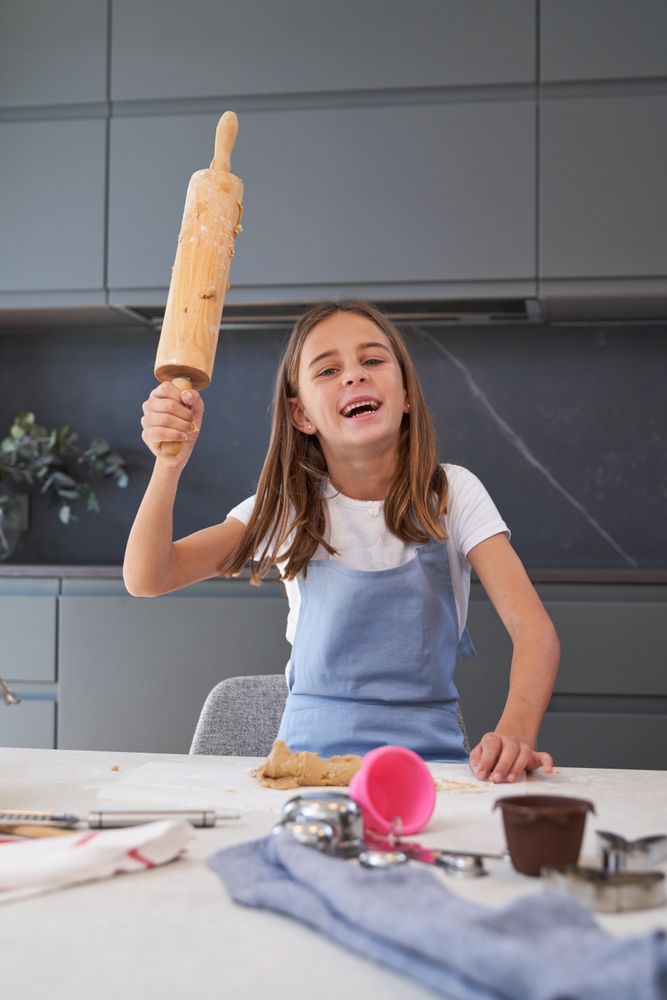Content girl with rolling pin in kitchen
