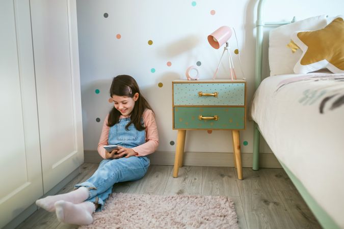 Girl laughing looking at the mobile sitting on the floor