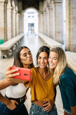 Three women taking selfie in Italian arch outdoors
