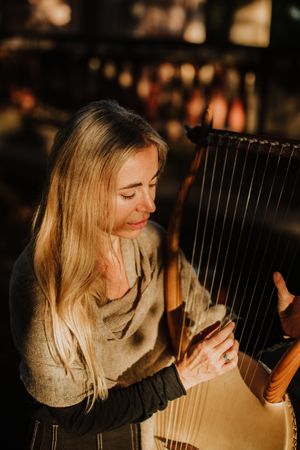 Sensual female musician playing lyre in garden