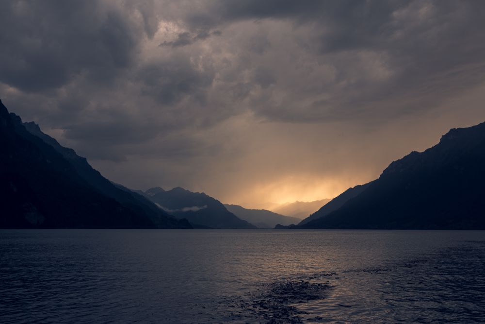 Gray water of lake in dark mountains under cloudy sky
