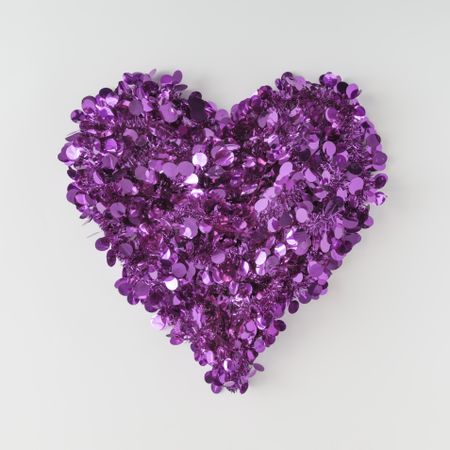 Purple confetti shaped in heart on light background