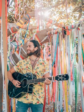 Man playing guitar under decorated tree