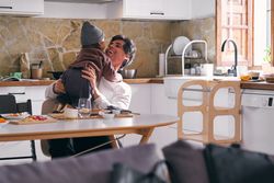 Happy father embracing unrecognizable daughter in kitchen