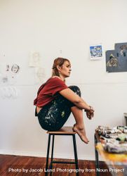 Side view of woman sitting on stool in her art studio bG9Ox5