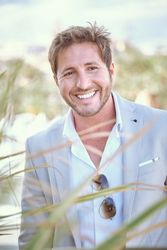 Cheerful man in elegant suit standing in front of green plants