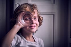 Positive little kid smiling and looking at camera through glass