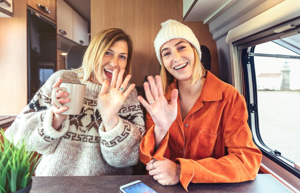 Women in orange shirt and woolen sweater sitting and waving in van