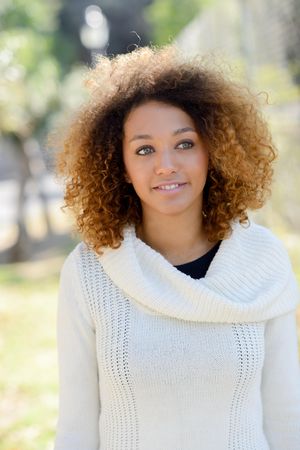 Female in sweater standing outside in park with selective focus