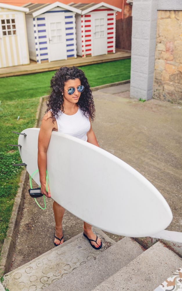 Brunette female surfer walking with surfboard