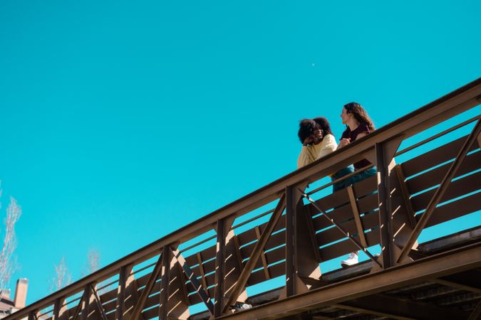 Two women talking on a bridge.