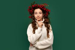 Girl wearing red berry wreath, posing with curious expression