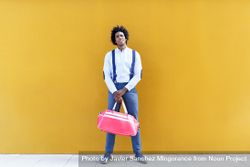 Man standing tall with sports bag standing in front of yellow wall 4Ae2W4