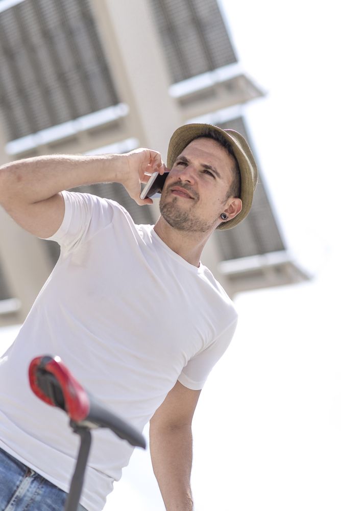 Shot looking up at man talking on phone under modern building