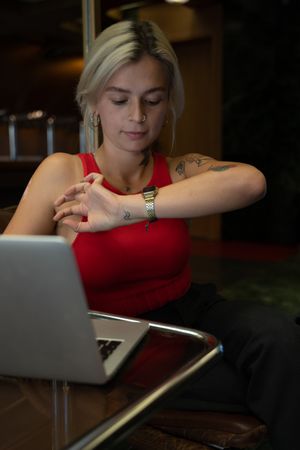 Spanish student checking the time while sitting at a table near computer