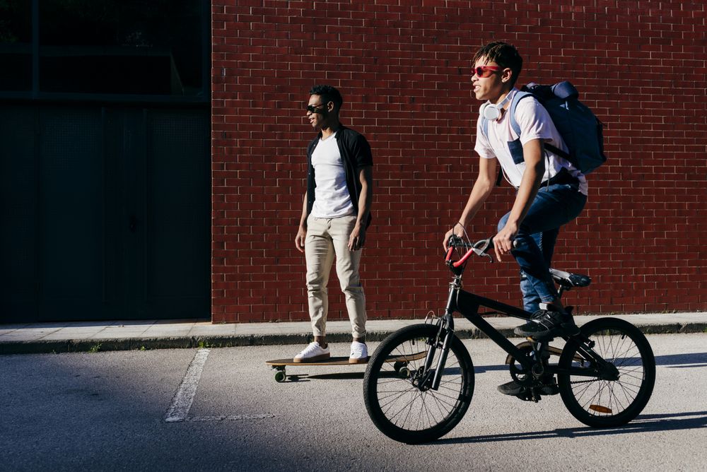 Young Black men riding bicycle and skateboard