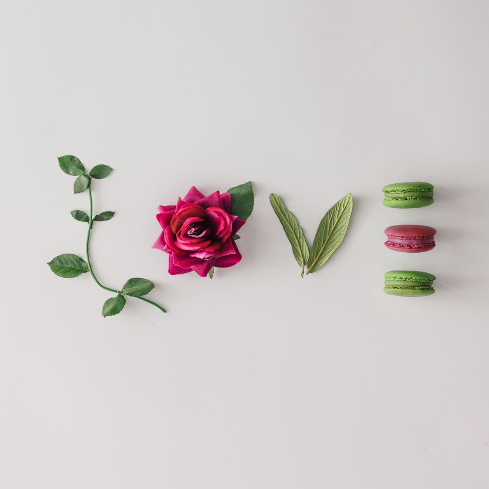 Word LOVE made out of flower, leaves and macarons