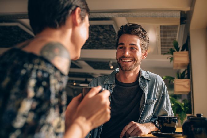 Man smiling at woman over drinks at a coffeeshop