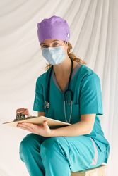 Woman in mask writing on clipboard