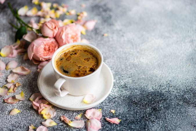 Pink roses on delicate table setting with coffee cup on grey counter