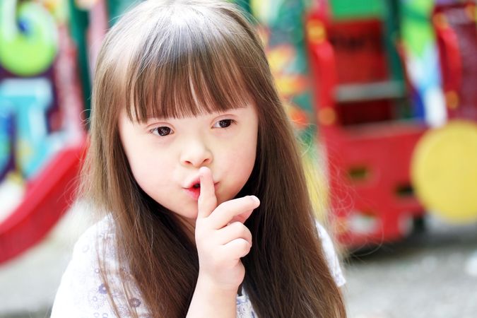 Young girl with Down syndrome saying “shh”