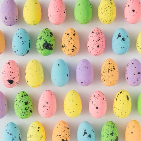 Rows of pastel Easter eggs on light background