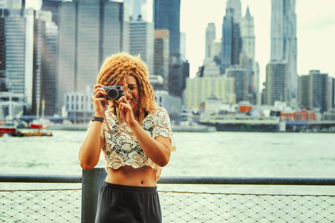 Black woman photographer taking photos with Manhattan skyscrapers in the background