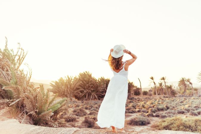 Woman in white dress in dry field in sunlight