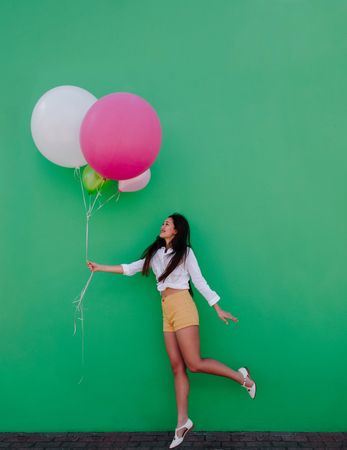 Smiling young woman holding a bunch of colorful balloons
