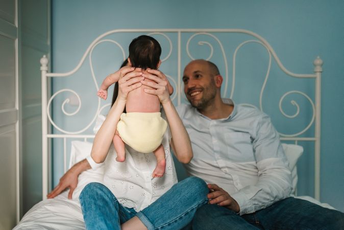 Parents hugging baby on bed