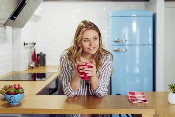 Young woman holding hot tea in kitchen