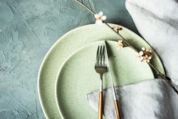 Top view of silverware on spring table setting blooming tree branch on grey table