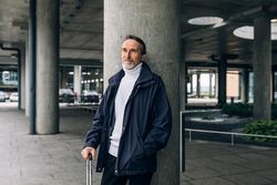 Stylish mature tourist standing leaning on pillar outside