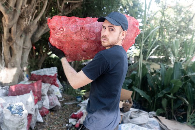 Young Man Handling Glass Recycled Bottles at Recycling Facility. Serious attitude