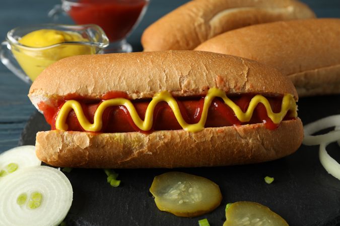 Tasty hot dog and ingredients on wooden background