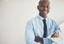 Man in shirt and tie smiling with arms crossed