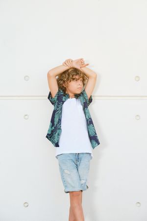 Stylish boy in trendy outfit against wall
