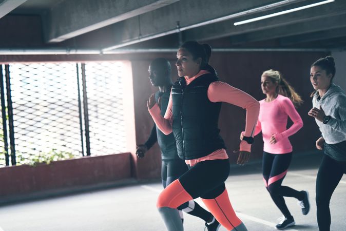 Woman in athletic gear leading multi-ethnic group of people running