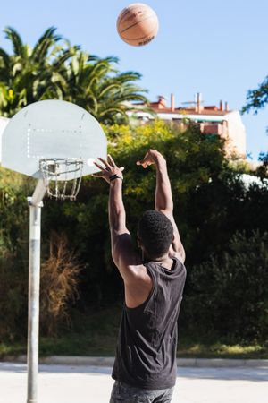 Anonymous Black man playing basketball on sports ground