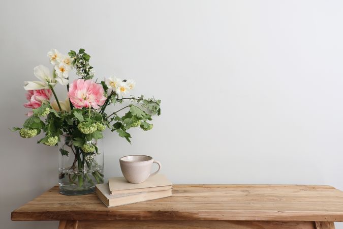 Table with cup of tea and vase of pink flowers