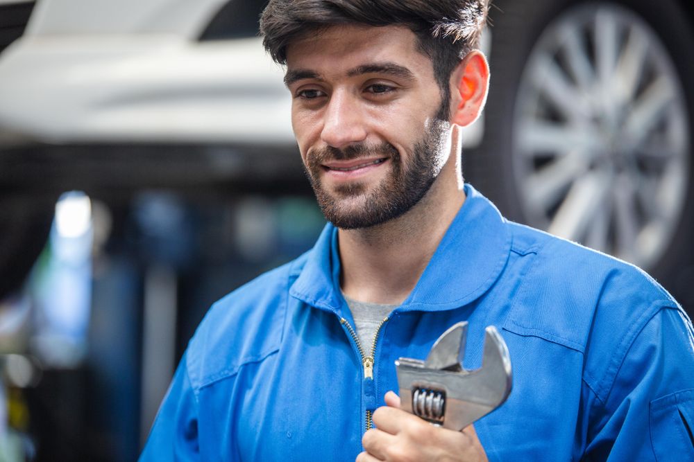 Happy male mechanic holding wrench at auto garage