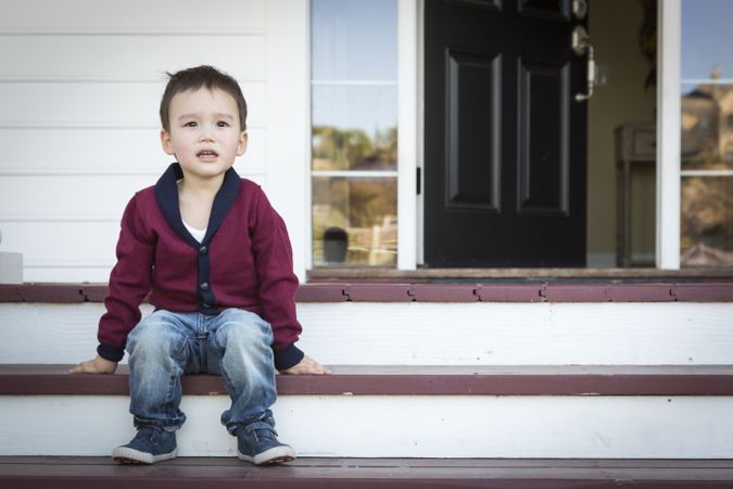 Biracial Boy Sitting on Front Porch Steps